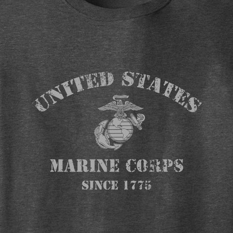 Close-up of a dark heather gray t-shirt featuring a distressed white graphic print of the United States Marine Corps Eagle, Globe, and Anchor emblem with the text 'UNITED STATES MARINE CORPS SINCE 1775'.