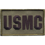 An embroidered rectangular patch with the letters 'USMC' in dark brown on an olive drab background, finished with a matching olive drab border.