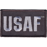 An embroidered rectangular patch with the letters USAF in light gray on a dark charcoal background, shown on a plain white background.