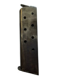A used metal rifle magazine with a dark, worn finish, photographed vertically against a light gray background.