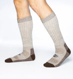 Pair of beige socks with brown accents worn by a person on a white background