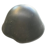 A dark olive green military-style helmet resting on a concrete floor.
