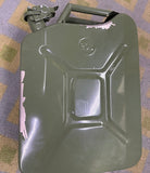 An olive green metal jerry can with a hinged lid and carrying handle, resting on a patterned purple and beige carpet.