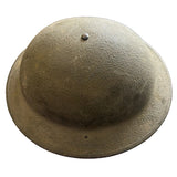 A vintage olive drab military helmet, likely World War II era, resting on a concrete floor.