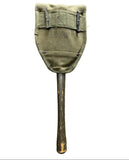 An olive green canvas shield or paddle-shaped cover with metal clips and a long dark wooden handle, laid flat on a gray concrete surface.
