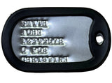 A black plastic dog tag with a silver metal insert, featuring customizable text fields and a hanging hole, shown on a textured beige background.