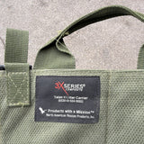 Close-up of an olive green woven fabric carrier bag with a black sewn-in label reading 3X Series Talon II Inter Carrier.