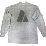 Gray long-sleeve shirt with a black triangle logo on a concrete floor