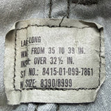 Close-up of a sewn fabric garment label inside a light gray or silver-toned textile item, showing printed measurements and sizing information.