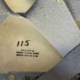 Close-up of the interior lining of a light blue woven hat, showing a beige paper label with handwritten '115' and small metal eyelets.