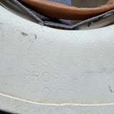 Close-up of a white molded plastic component with embossed text reading 'PROPER' and a tan strap or trim running along the top edge.