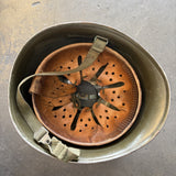 A vintage military-style helmet shown from above, with a worn tan leather ventilator insert and straps inside.
