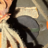 Close-up of the interior lining of a brown leather boot or shoe, showing a circular black insert, a small paper label with German text, and surrounding tan and gray fabric lining.